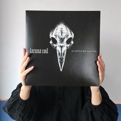 Młoda kobieta trzyma w ręce płytę zespołu Lacuna Coil Sleepless Empire. Nie widać jej twarzy. Zasłania ją płyta winylowa.